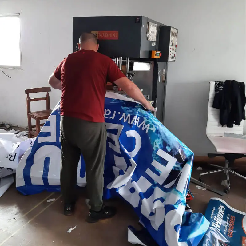 Operario realizando sellado de lona PVC en taller de impresión publicitaria